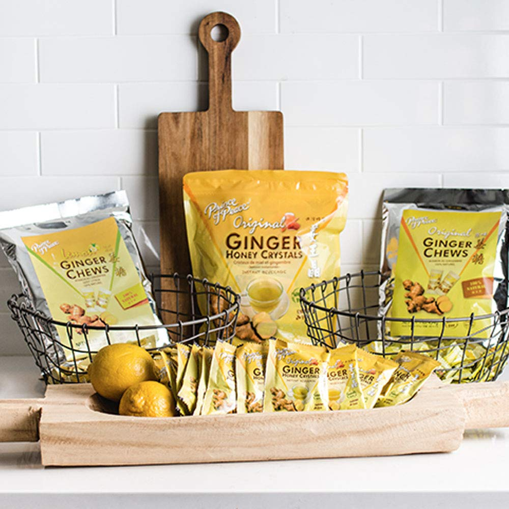 A kitchen counter with ginger chews, lemons, and a wooden tray arranged together — a simple, natural comfort used for nausea and stomach relief.